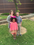 Elizabeth Ernster posing with her brother and sister on grass