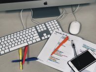 Picture of an Apple keyboard, a planner, highlighter pens and a smartphone.