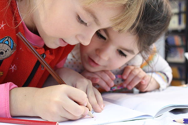 Two kids coloring on a table