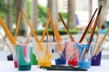 A collection of brushes and paints on a desk.