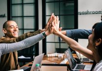 Photo of people in a group meeting giving high fives..